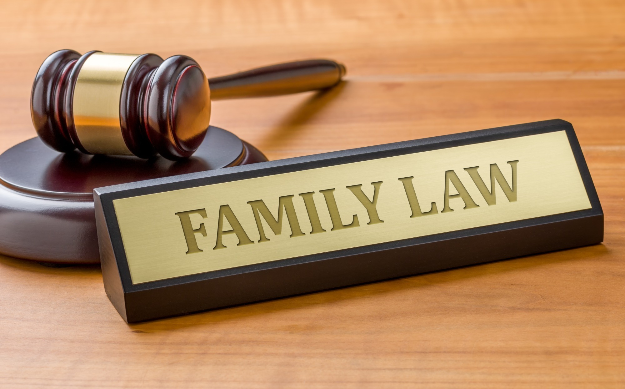 A wooden desk displays a gavel beside a nameplate engraved with "FAMILY LAW," symbolizing legal practice in family matters.